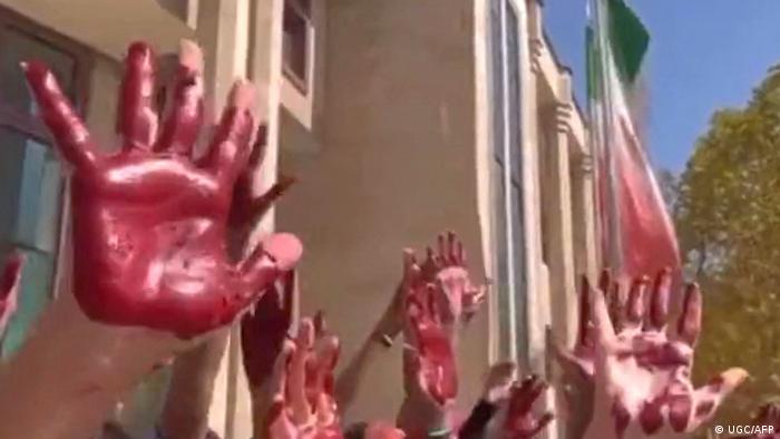 Cette capture d'image d'une vidéo UGC mise à disposition sur Twitter le 9 octobre 2022 montre des étudiants iraniens de la Faculté des arts de l'Université Azad de Téhéran participant à une manifestation avec leurs paumes couvertes de peinture rouge pour symboliser le sang.
