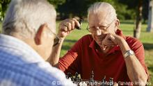 Active retired people, two senior men playing chess at park