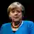 Foto de Merkel. Ela usa colar de pedras e roupa azul. 