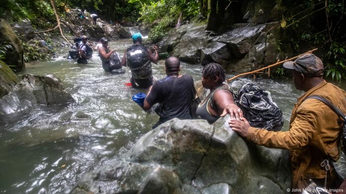 Haitian migrants wade through water will crossing jungle in the Darien Gap