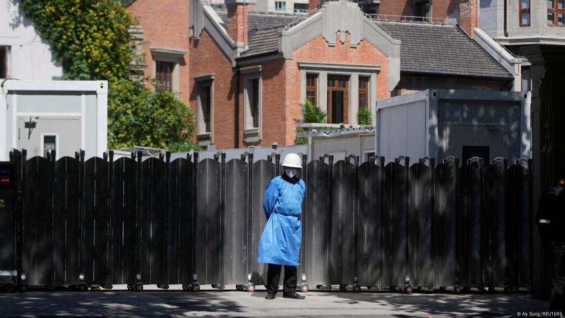 Homem com capacete, máscara e roupa de proteção azul diante de muro