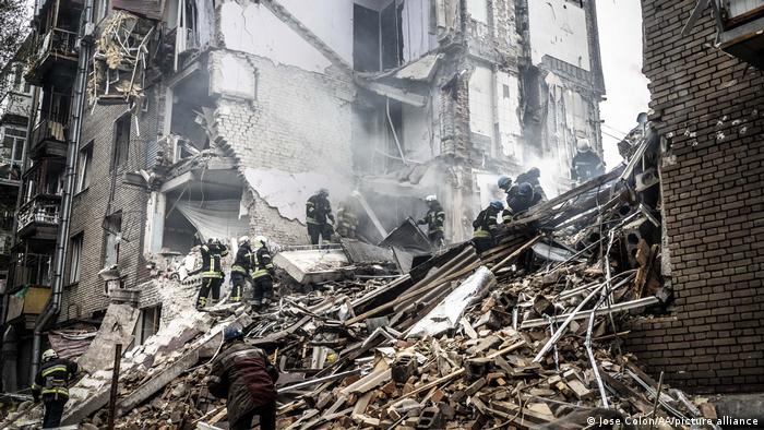 Feuerwehrleute suchen in Trümmern eines Hauses nach Bewohnern 