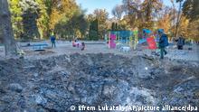A man passes past a rocket crater at playground in city park in center Kyiv, Ukraine, Tuesday, Oct. 11, 2022. Russia on Monday retaliated for an attack on a critical bridge by unleashing its most widespread strikes against Ukraine in months. (AP Photo/Efrem Lukatsky)
