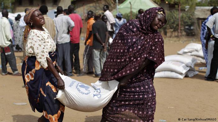 Südsudan Juba Lebensmittelkrise. Zwei Frauen tragen einen Sack mit Getreide aus einer Lieferung des World Food Programms WFP