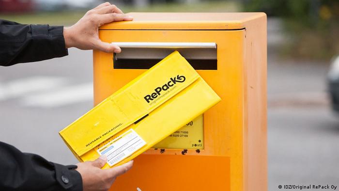 A yellow envelope, folded to the size of a letter, is dropped into a mailbox 