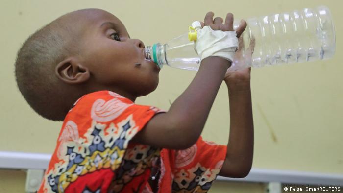 Afrika I Hunger und Unterernährung in Somalia. Auf dem Foto ist ein dreijähriger Junge in Somalia zu sehen, der aus einer Plastikflasche trinkt. An der rechten Hand ist eine Kanüle und ein Verband zu sehen.
