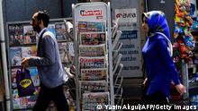 People walk in fronter of a kiosk selling the daily newspapers a day after the presidential and parliamentary elections in Istanbul on June 25, 2018 - Turkish incumbent president on June 25, 2018 celebrated winning five more years in office with sweeping new powers after a decisive election victory, as his main rival accepted the outcome despite bitter complaints over the conduct of the campaign. (Photo by Yasin AKGUL / AFP) (Photo credit should read YASIN AKGUL/AFP via Getty Images)