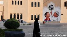 A woman walks past a mural in the Katara Cultural Village, in Qatar's capital Doha, on October 11, 2022 ahead of the FIFA 2022 football World Cup. - Katara is home to an open amphitheatre, an opera house, a multi-purpose cinema, a multi-purpose conference hall and a museum showcasing Qatar's maritime heritage. (Photo by Giuseppe CACACE / AFP)