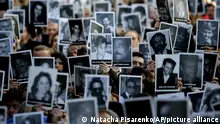 People hold up pictures of people who died in the bombing of the AMIA Jewish center that killed 85 people, as they commemorate the attack's 22nd anniversary in Buenos Aires, Argentina, Monday, July 18, 2016. The 1994 attack is still unsolved. (AP Photo/Natacha Pisarenko)