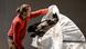 A man in a red sweater removes white foil from a metal sculpture of a horse