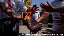 An Iranian woman burns her Iranian passport during a protest against the death of Iranian Mahsa Amini, outside Iran's embassy in Santiago, Chile, Friday, Oct. 14, 2022. The 22-year-old died in Iran while in police custody on Sept. 16 after her arrest three days prior by Iran's morality police for allegedly violating its strictly-enforced dress code. (AP Photo/Esteban Felix)