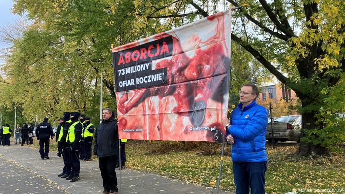 Zwei männliche Abtreibungsgegner demonstrieren mit einem großen Transparent, auf dem ein angeblich abgetriebener Fötus gezeigt wird, vor dem Gericht in Warschau