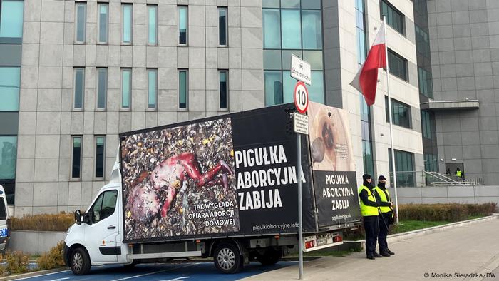 Ein Lastwagen mit einem großen Plakat, das einen abgetriebenen Fötus zeigen will, steht vor einem Gerichtsgebäude in Warschau, zwei Sicherheitskräfte schützen den LKW