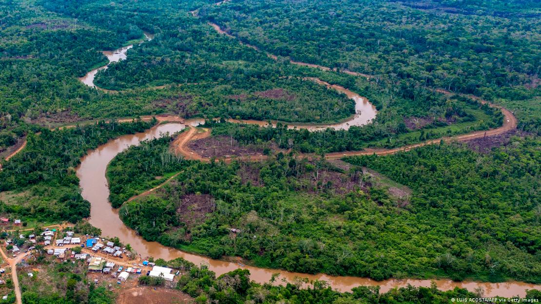 Vista aérea de uma região de selva com poucas casas à beira de um rio