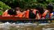 Pessoas de coletes salva-vidas laranja dormem sentadas em uma canoa