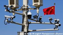 A Chinese national flag flutters near the surveillance cameras mounted on a lamp post in Tiananmen Square in Beijing, Friday, March 15, 2019. Chinese Premier Li Keqiang on Friday denied Beijing tells its companies to spy abroad, refuting U.S. warnings that Chinese technology suppliers might be a security risk. (AP Photo/Andy Wong)