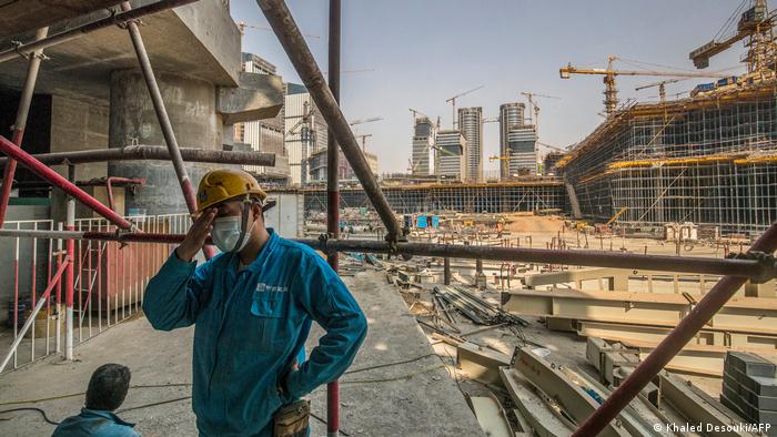 Ein chinesischer Arbeiter steht mit Helm und Blaumann vor der riesigen Baustelle der neuen Hauptstadt Ägyptens. Sie wird 45 Kilometer östlich von Kairo errichtet. 