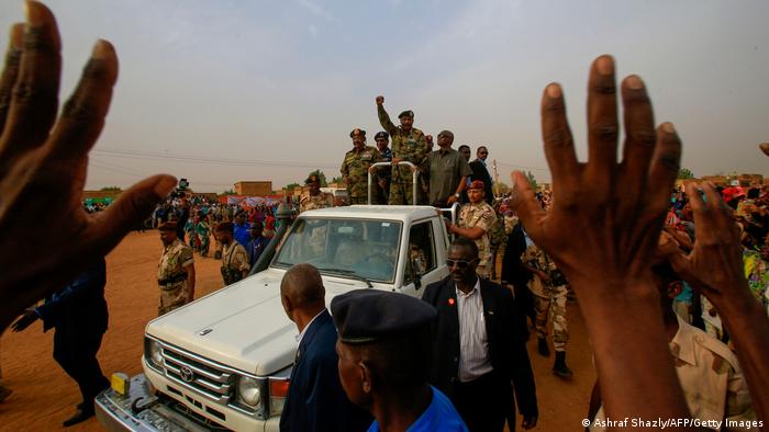 General Abdel Fattah al-Burhan, der Vorsitzende der Militärregierung, reckt auf einem Wagen vor Anhängern die Faust in die Höhe 