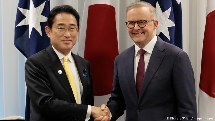 Japans Premierminister Fumio Kishida und der australische Premierminister Anthony Albanese reichen sich vor den Fahnen beider Länder die Hände