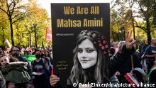 Ein Teilnehmer der Großdemonstration Solidarität mit den Protestierenden im Iran hält am Großen Stern ein Plakat mit der Aufschrift We Are All Mahsa Amini. Von dort ziehen sie durch das Regierungsviertel.