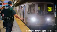 FILE - As a subway train enters the Canal St. Q and N station, a NYPD transit officer from the anti terrorism unit gestures to the driver, Tuesday, May 24, 2022, in New York. In the aftermath of a mass shooting on the subway, New York Mayor Eric Adams has floated a high-tech idea of deploying scanners that can spot someone carrying a gun into the transit system before they have a chance to use it. (AP Photo/Mary Altaffer, File)