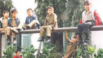 Chinesische Kinder auf einer Mauer bei einem Spielplatz in Kolkata