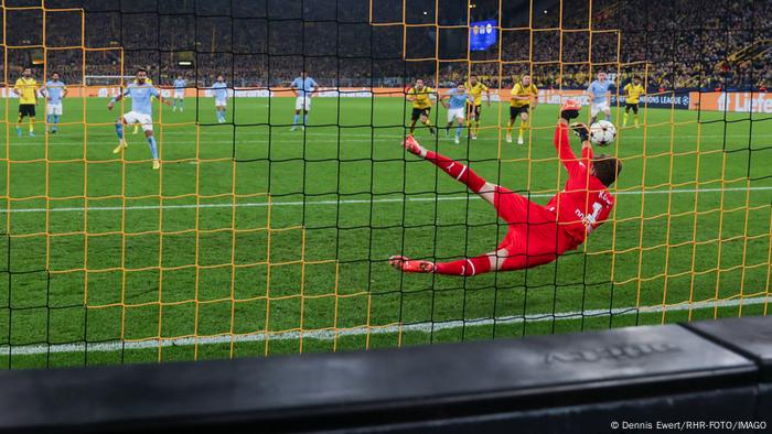 Riyad Mahrez schießt für Manchester City einen Elfmeter, BVB-Torhüter Gregor Kobel springt nach recht und faustet den Ball weg