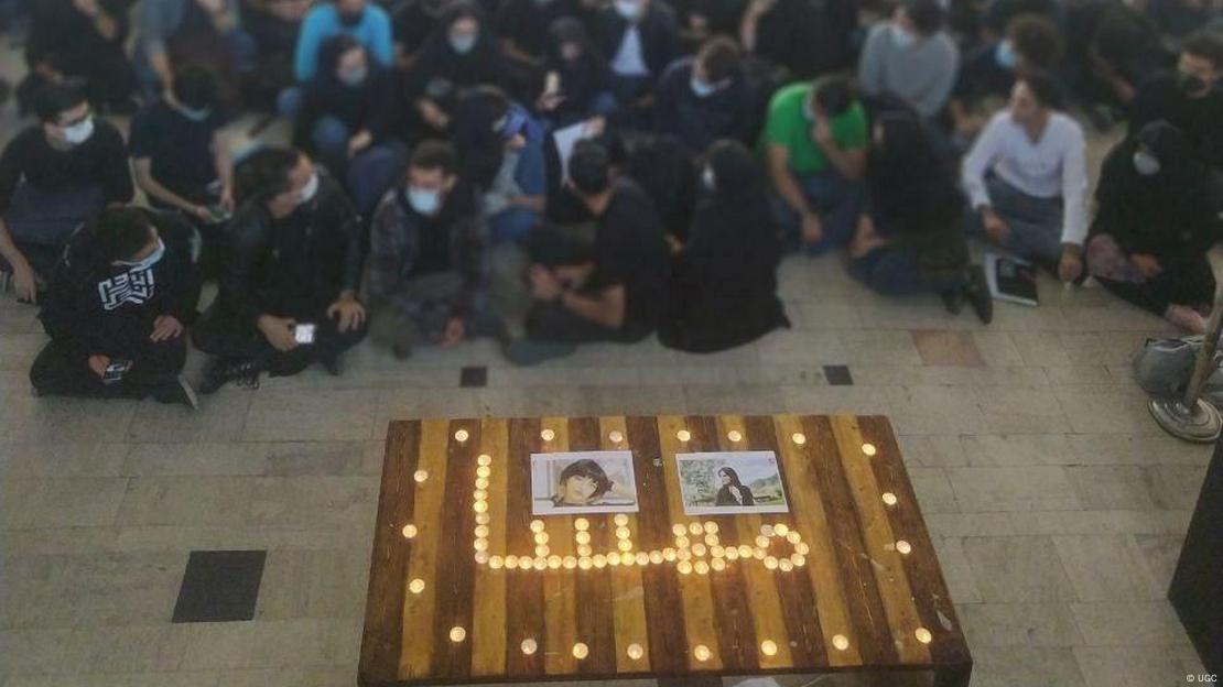 Candles surrounding photos of Jina Mahsa Amini with students sitting nearby