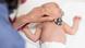 A doctor put a stethoscope on a baby lying on his back during a medical checkup A doctor put a stethoscope on a baby lying on his back during a medical checkup