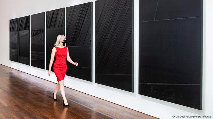 Frau geht an Gemälden von Pierre Soulages vorbei. Frau geht an Gemälden von Pierre Soulages vorbei.
