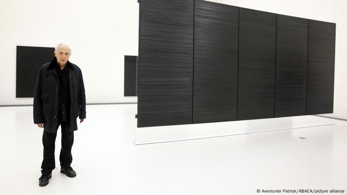 Pierre Soulages steht vor seinen schwarzen Leinwänden. Pierre Soulages steht vor seinen schwarzen Leinwänden.