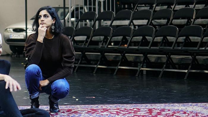 Sonia Hossein-Pour sitzt in der Hocke, hinter sich Reihen leerer Stühle.