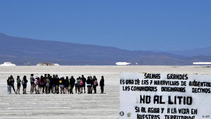 Grupo de turistas al fondo con el cartel en primer plano.