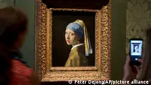 FILE- Visitors take pictures of Johannes Vermeer's Girl with a Pearl Earring (approx. 1665) during a preview for the press of the renovated Mauritshuis in The Hague, Netherlands, June 20, 2014. The Vermeer masterpiece “Girl with a Pearl Earring” has become the latest artwork targetted by climate activists in a protest at the Mauritshuis museum in The Hague on Thursday, Oct. 27, 2022. The museum did not immediately return calls and emails for comment after a video of the protest was posted on Twitter. (AP Photo/Peter Dejong, file)