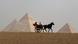 Tourists ride a horse-drawn cart in front of the Pyramids in Giza, on the outskirts of Cairo, Egypt. Tourists ride a horse-drawn cart in front of the Pyramids in Giza, on the outskirts of Cairo, Egypt.