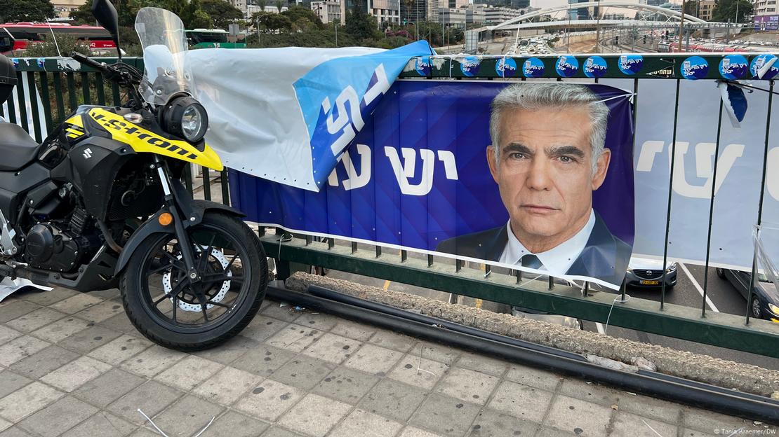 A motorbike alongside a bridge railing with a banner of a politician
