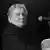 Schwarz-weiß-Foto von Jerry Lee Lewis, der am klavier sitzt und in die Kamera blickt.