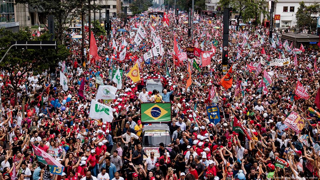 Lula atop a car at a campaign rally, surrounded by thousands of supporters wearing red