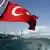 Турецкий флаг с видом на мост Ататюрка в Стамбуле 