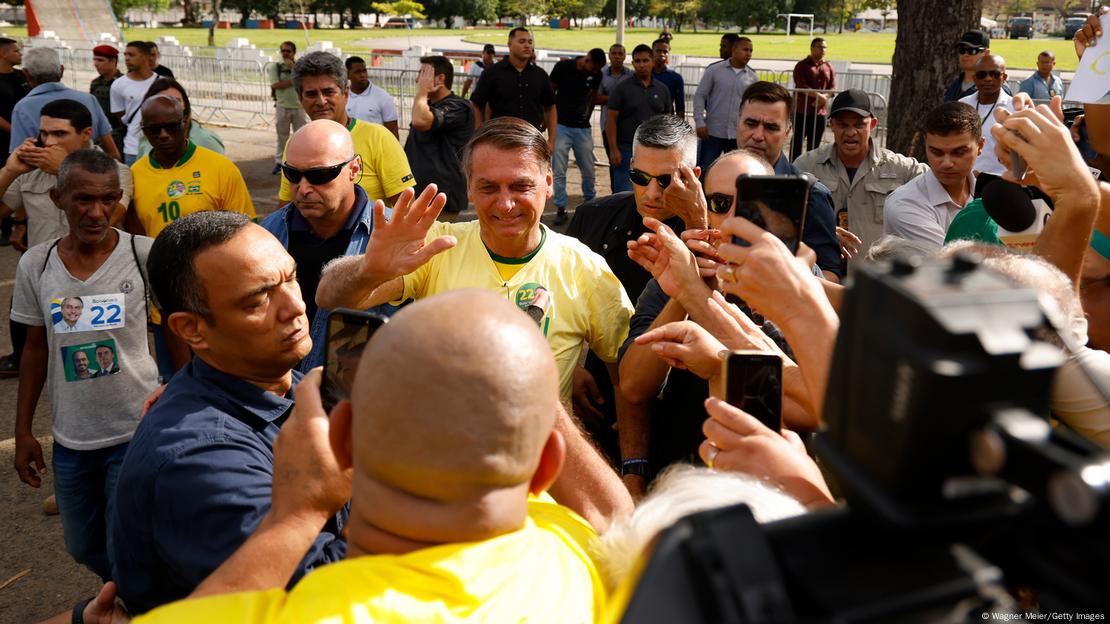 Bolsonaro, surrounded by security, waves at his supporters in front of a polling station in Rio de Janeiro 