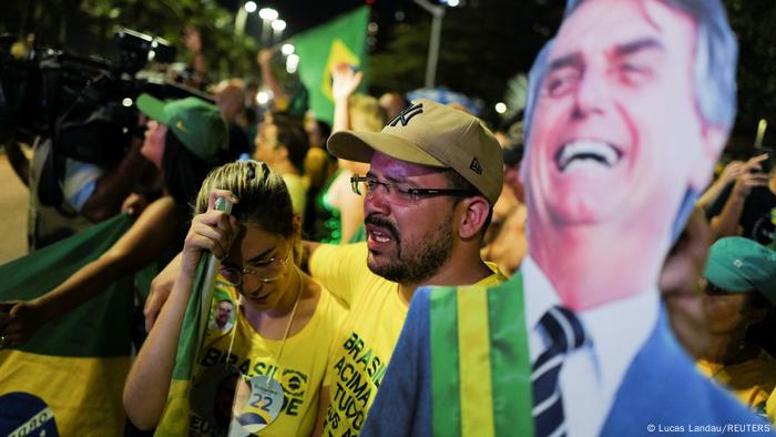 Unterstützer von Jair Bolsonaro mit einer Pappfigur von ihm schauen traurig