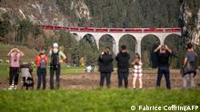 Members of the public capture images as a 1910-metre-long train with 100 cars passes the Landwasser Viaduct, after Bergun, on October 29, 2022, during a record attempt by the Rhaetian Railway (RhB) of the World's longest passenger train, to mark the Swiss railway operator's 175th anniversary. - The record attempt is carried out on the Albula Line, from Preda to Thusis, crossing one of the most spectacular railways in the world, recognised as a Unesco World Heritage Site. (Photo by Fabrice COFFRINI / AFP)