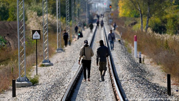 Personas migrantes sobre una vía ferroviaria en los Balcanes Occidentales