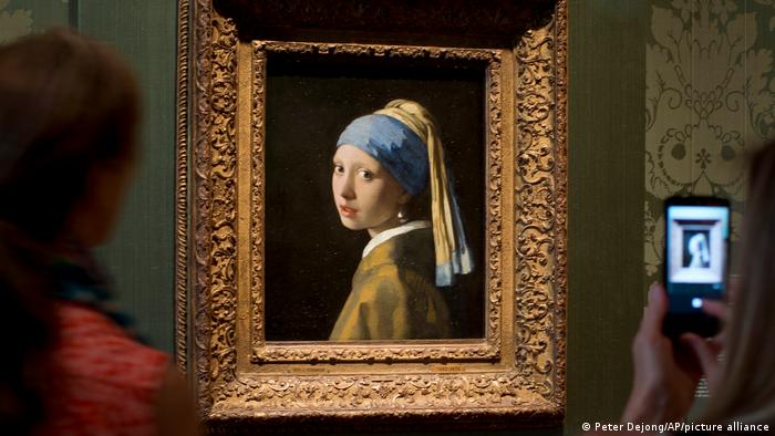 Gemälde, das ein Mädchen mit einem Perlenohrgehänge abbildet, in goldenem Rahmen.