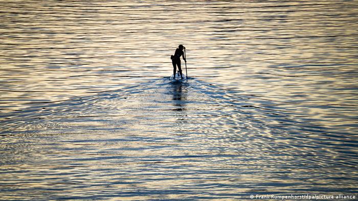 Una mujer practica surf a remo en el río Meno, el afluente que cruza la ciudad de Frankfurt, en Alemania. La deportista aprovecha que cae la noche y las aguas se tranquilizan de otras embarcaciones para practicar con más tranquilidad.
