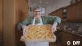 Eine ältere Frau hält einen Blechkuchen in den Händen (Quelle: DW)