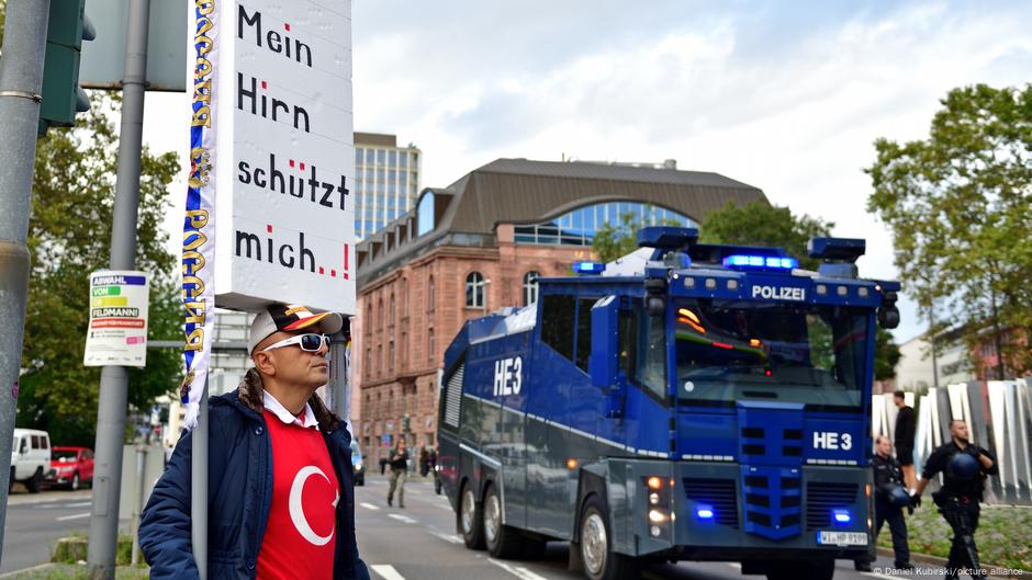 „Moj mozak me štiti“ piše na plakatu ovog demonstranta u Frankfurtu pored policijskog vozila