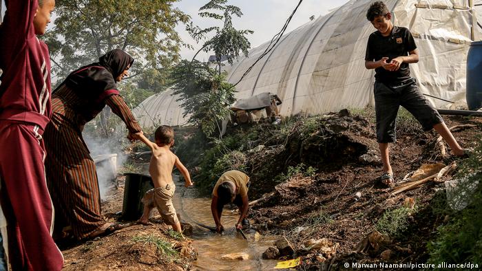 Libanon: Eine syrische Mutter zieht ihren Sohn aus einer verseuchten Wasserführung in der Nähe ihres Zeltes in einem Flüchtlingslager