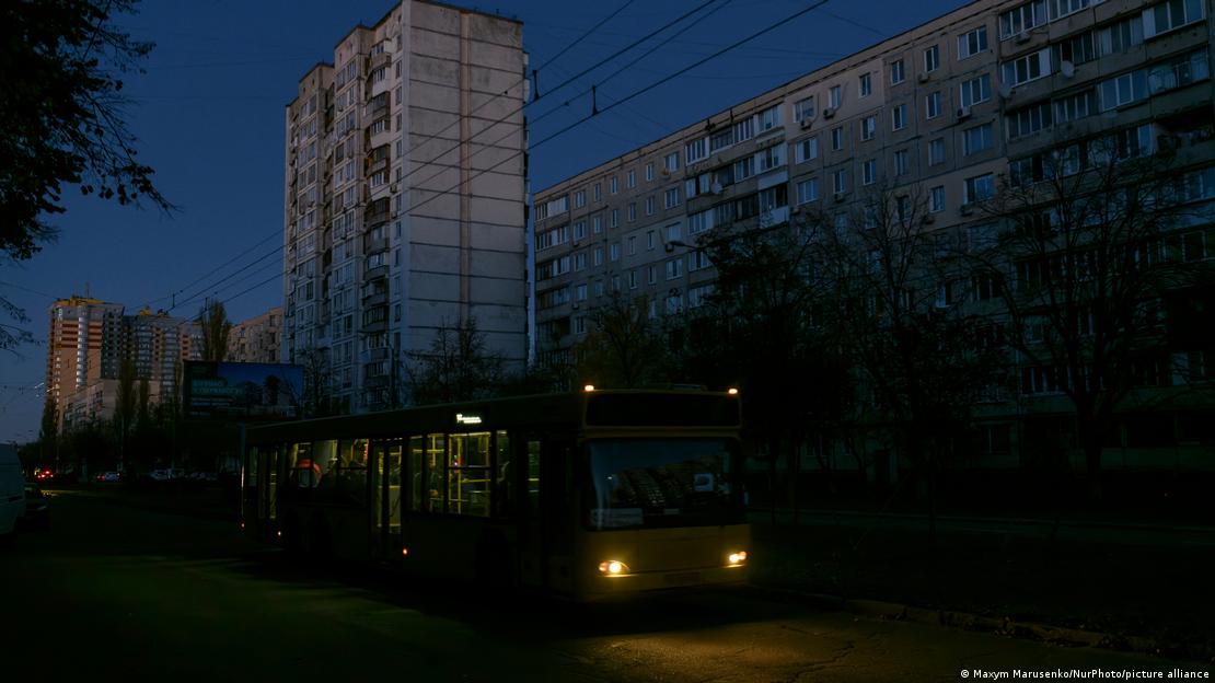 ônibus circula por rua escura en frente a prédio de apartamentos
