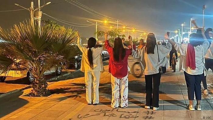 Protestierende Frauen ohne Kopfbedeckung (von hinten zu sehen) auf der Straße.